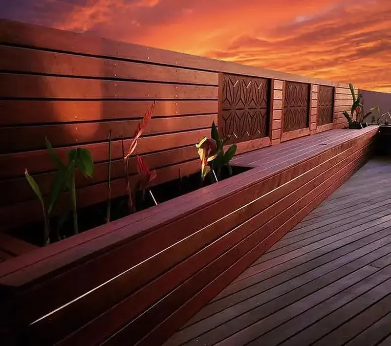 Merbau deck with a slatted timber feature wall and planter at sunset