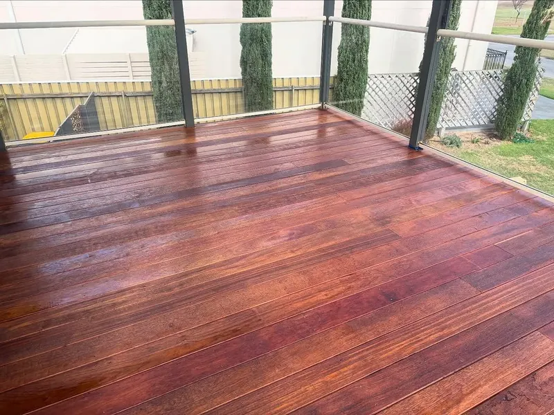 Red timber deck with a glass balustrade, freshly oiled